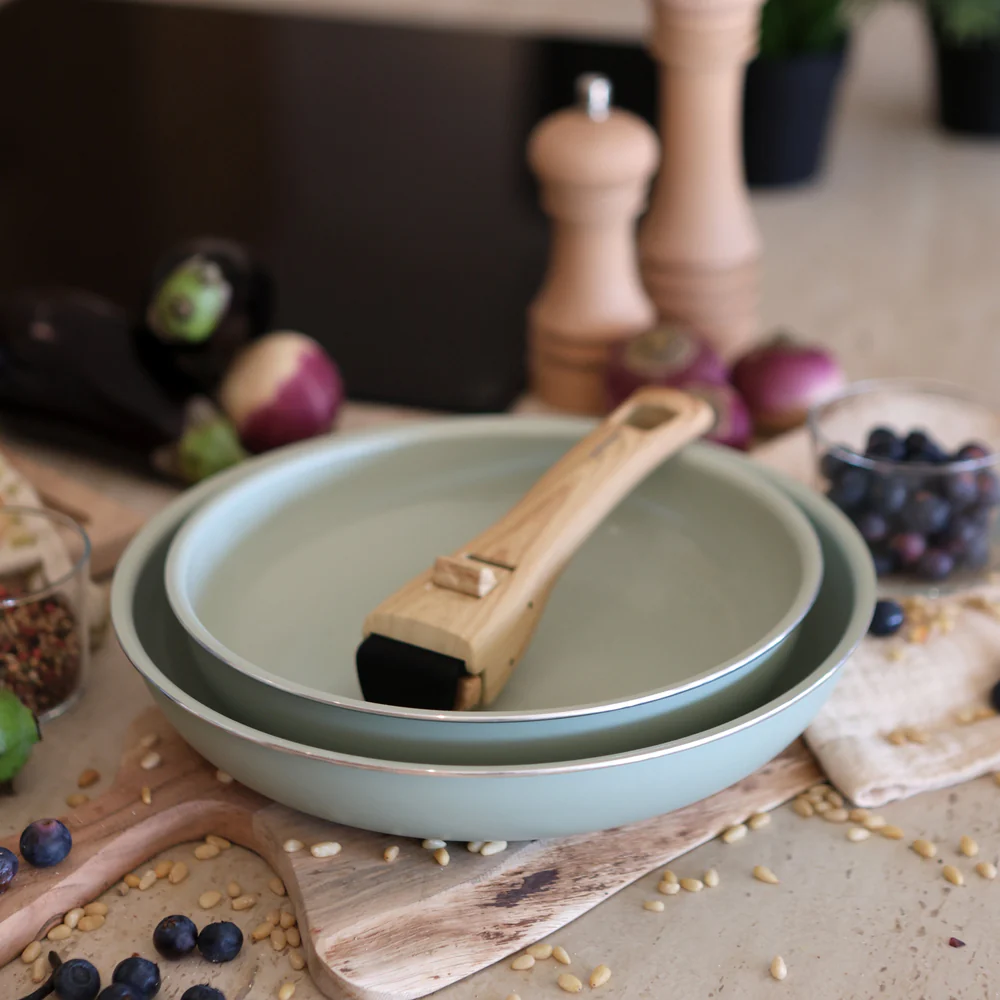 Casseroles bleu glacier avec manche en bois posées sur une gazinière, intégrées dans une cuisine moderne au style Slow déco.